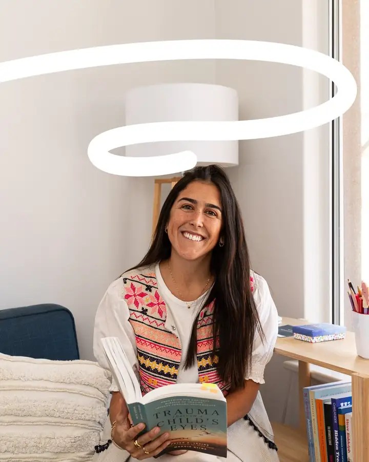 Francisca Lessa Stewart, Registered Psychologist, smiling while reading in her practice room